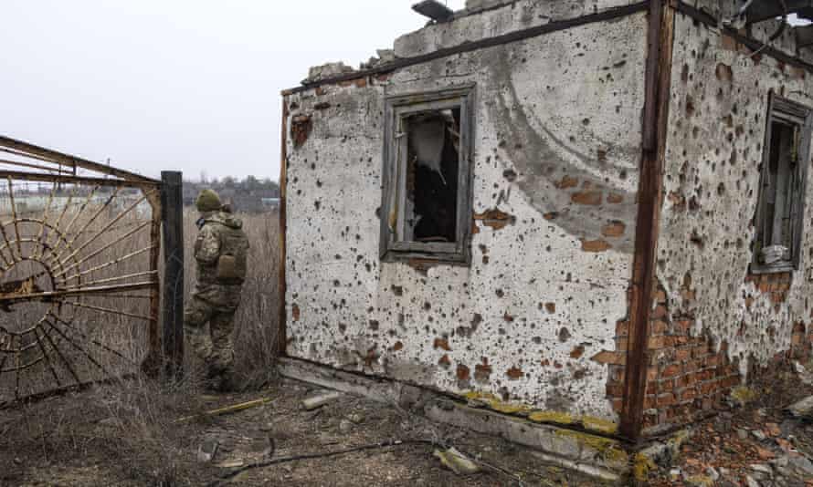 Украинский солдат проходит мимо заброшенного дома на передовой.