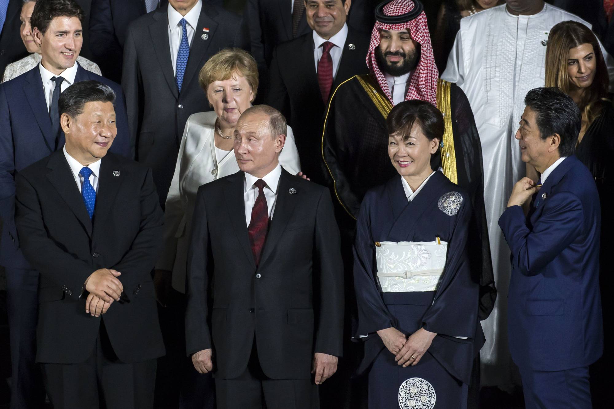 Слева направо: премьер-министр Канады Джастин Трюдо, президент Китая Си Цзиньпин, бывший канцлер Германии Ангела Меркель, президент России Владимир Путин, наследный принц Саудовской Аравии Мухаммед бен Салман, Аки Абэ, жена бывшего премьер-министра Японии Синдзо Абэ, и Синдзо.  Абэ позирует с другими лидерами и делегатами для семейного фото на саммите G20 в Осаке в июне 2019 года. |  Блумберг