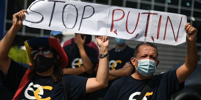 Протестующие проводят "остановить путина" Баннер во время акции протеста против вторжения России в Украину у консульства Европейского Союза в Каракасе, Венесуэла, в четверг, 3 марта 2022 года. 