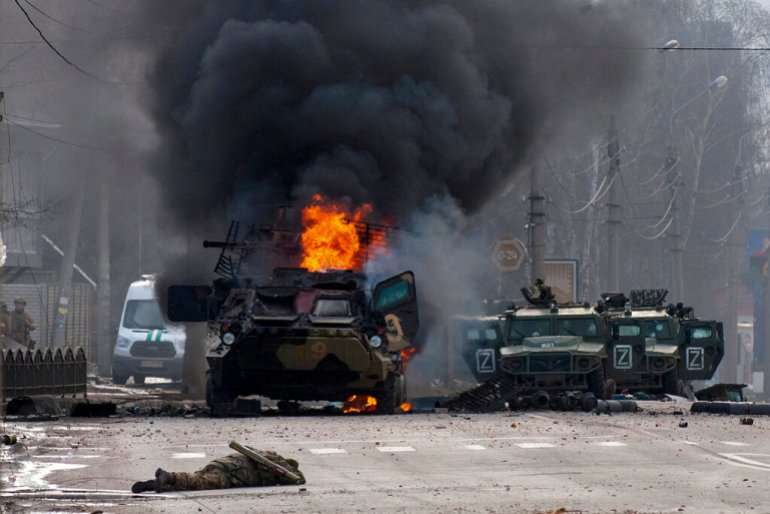 Российский бронетранспортер горит среди поврежденных и брошенных легких служебных автомобилей после боев в Харькове, Украина.