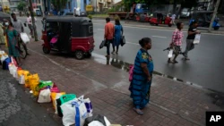 Люди стоят в очереди со своими посылками в ожидании покупки керосина возле заправочной станции в Коломбо, Шри-Ланка, 11 июня 2022 года.